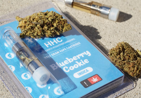 a blue package with marijuana buds and a blue container with a clear plastic tube